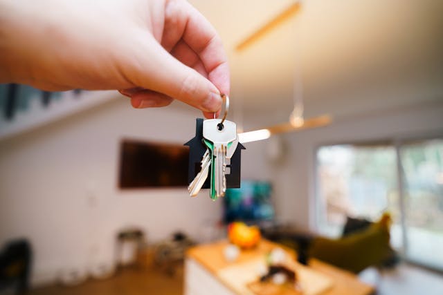 a hand holding up house keys in a living room