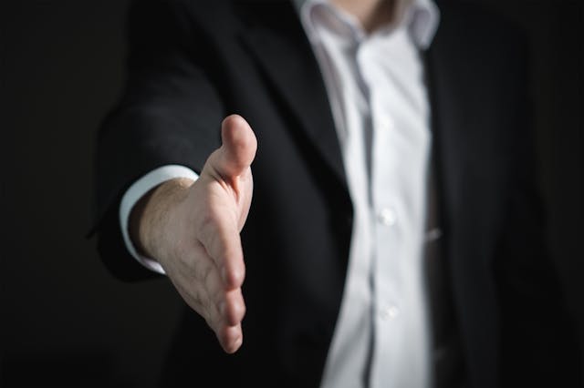 person in suit holding out hand