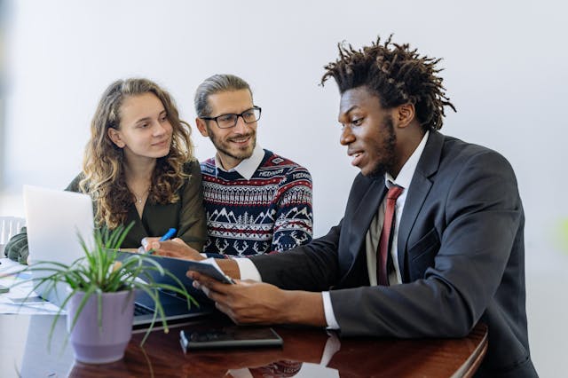 a man in a suit showing a couple a contract